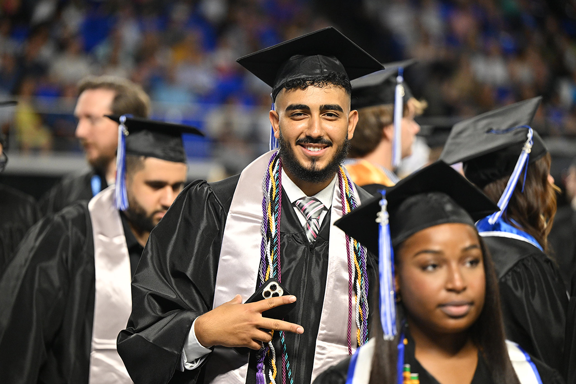 A proud Middle Tennessee State University graduate flashes the peace sign as he and other graduates march to their seats at the summer 2025 commencement ceremony held Saturday, Aug. 9, inside Murphy Center on campus in Murfreesboro, Tenn. (MTSU photo by James Cessna)