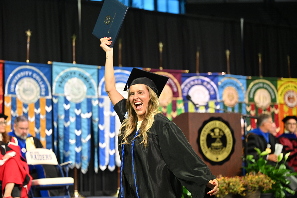 A proud Middle Tennessee State University graduate holds up her degree as she returns to her seat during the summer 2025 commencement ceremony held Saturday, Aug. 9, inside Murphy Center on campus in Murfreesboro, Tenn. (MTSU photo by James Cessna)