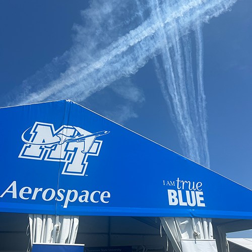 Contrails from participating aircraft at the 72nd EAA AirVenture aviation showcase held July 21-27 in Oshkosh, Wisc., are seen high above the Middle Tennessee State University exhibition tent on location for the weeklong event, known as “the world’s largest gathering of aviation enthusiasts.” (MTSU photo by Andrew Oppmann)