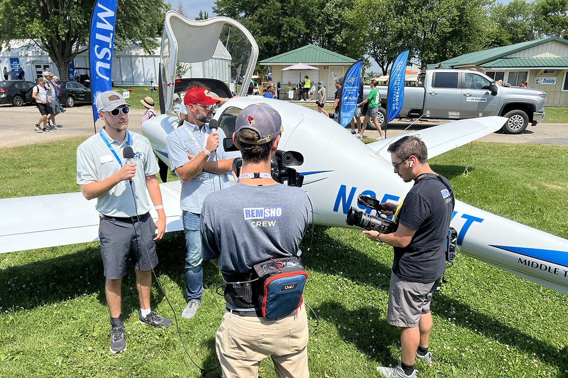 Jonathan Quinby, left, a junior Aerospace Pro Pilot at Middle Tennessee State University in Murfreesboro, Tenn., takes viewers of the Oshkosh Live livestreamed TV show on a tour of one of the university’s Diamond DA-40 training aircraft flown up to display at the 72nd EAA AirVenture in Oshkosh, Wis. Quinby was part of an MTSU delegation of students, faculty and staff that attended the July 21-27 event known as “the world’s largest gathering of aviation enthusiasts.” Next to Quinby is Oshkosh Live host Shawn Bean. (MTSU photo by Andrew Oppmann)