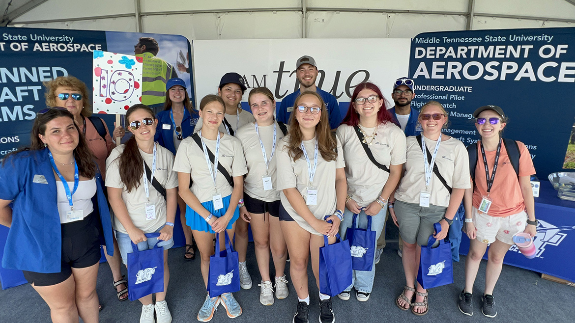 Representatives from the Aerospace Department at Middle Tennessee State University in Murfreesboro, Tenn., pose for a photo with a group of high school students and their bags of MTSU swag after they visited the university’s exhibition and information tent set up at the 72nd EAA AirVenture aviation showcase held July 21-27 in Oshkosh, Wis. MTSU Aerospace returned to the event with a delegation of faculty, staff and students to showcase the aerospace program. (MTSU photo by Andrew Oppmann)