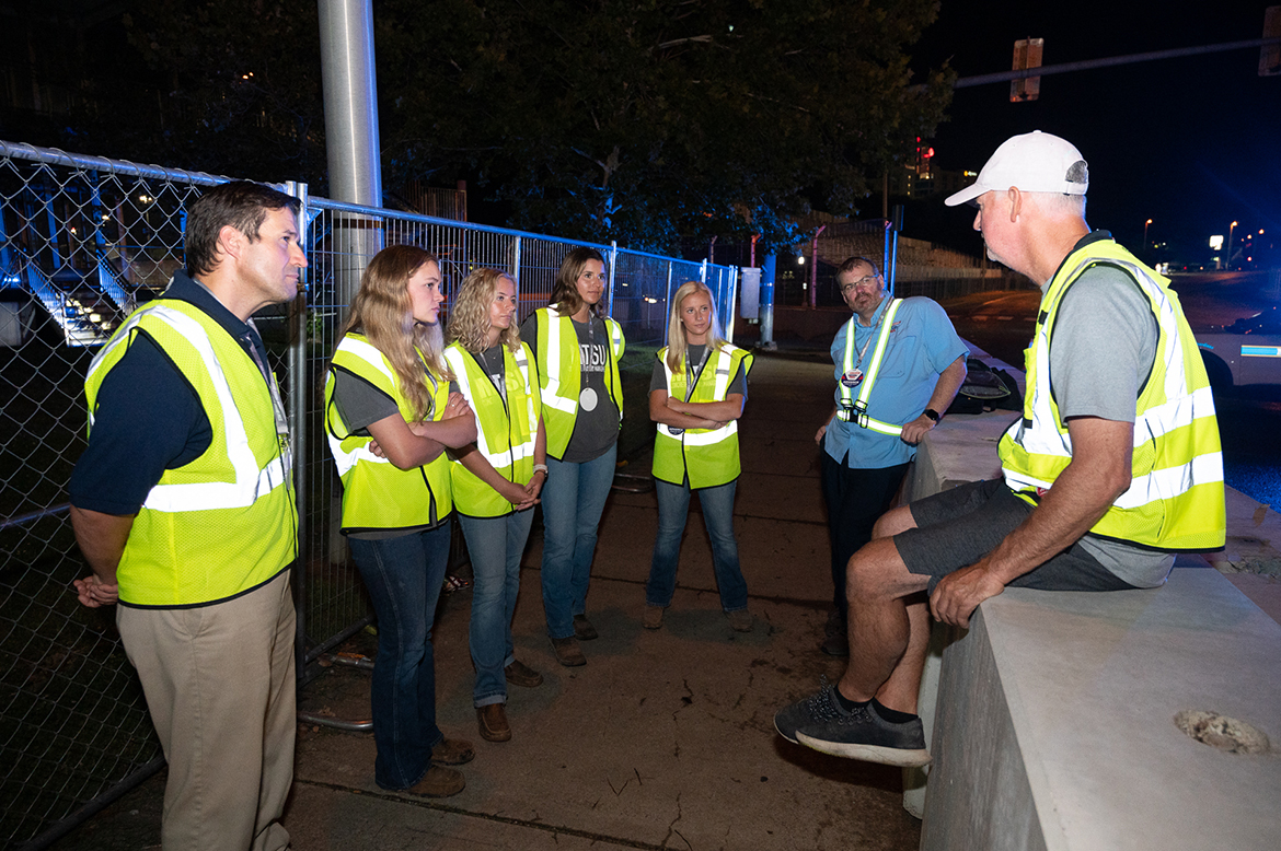 Tony Cotman, right, track designer for the Aug. 4-6 Big Machine Music City Grand Prix and previous two NTT IndyCar Series races in downtown Nashville, Tenn., explains about safety barriers and the importance of concrete utilized by track officials to Middle Tennessee State University Concrete Industry Management Director Jon Huddleston, left, students Ashlyne Roeger of Murfreesboro, Tenn., Claire Mullins of Fayetteville, Tenn., Arie Milam of Clarksville, Tenn., and Carlie Mullins of Fayetteville, and MTSU alumnus Charlie Legeman, senior sales director for the grand prix, during a recent nighttime visit. The concrete students will meet Cotman again Friday, Aug. 4. They have been part of a 10-week NASA internship this summer. (MTSU photo by James Cessna)