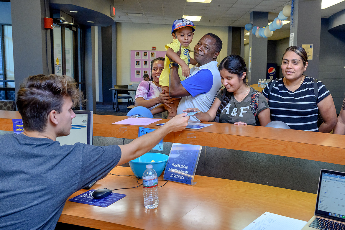 
As new Middle Tennessee State University freshman Daniela Gomez, second from right, checks in at the front desk, MTSU President Sidney A. McPhee, third from left, holds Zaid Gomez while the family waits to take her items to her room in Corlew Hall. The president assisted with students’ moving into campus on Wednesday, Aug. 23. (MTSU photo by J. Intintoli)