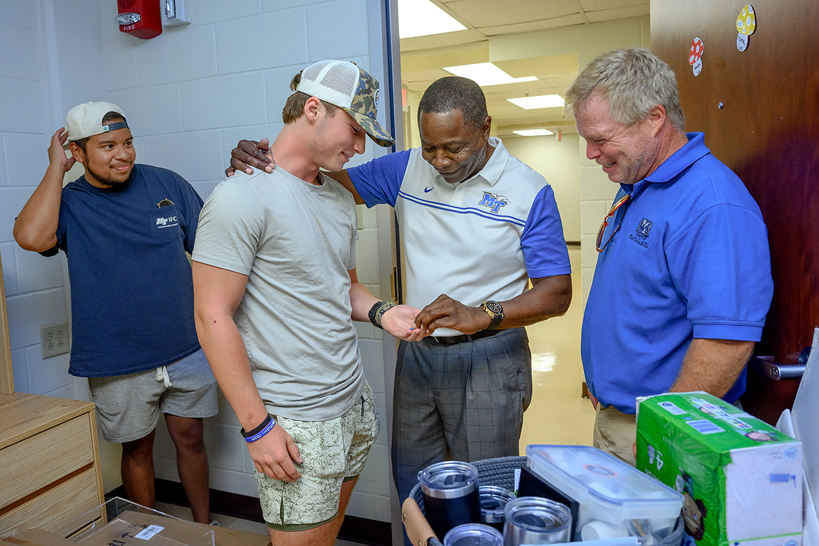 With Middle Tennessee State University student John Lyons, left, observing, new MTSU student Trey Kirk receives a President’s Pin from university President Sidney A. McPhee, while Joe Kirk shares the moment with his son during move-in on Wednesday, Aug. 23, in Corlew Hall. (MTSU photo by J. Intintoli)