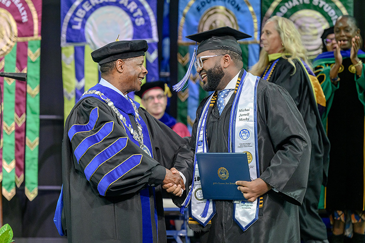 Middle Tennessee State University graduate and outgoing Student Government Association president, Michai Mosby, right, accepts his degree from MTSU President Sidney A. McPhee during the spring 2025 commencement ceremony held Friday, May 9, inside Murphy Center on the MTSU campus in Murfreesboro, Tenn. (MTSU photo by J. Intintoli)