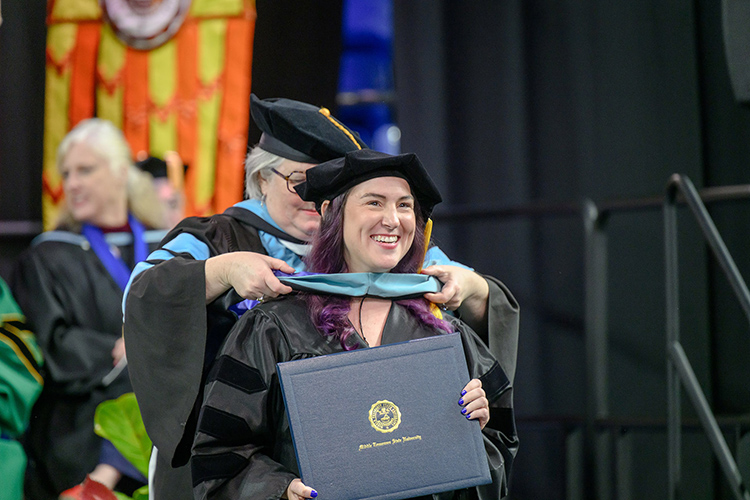 Middle Tennessee State University graduate and doctorate recipient Rachel Catherine Adams is all smiles as she’s hooded by her professor Kim Godwin during the spring 2025 commencement ceremony held Friday, May 9, inside Murphy Center on the MTSU campus in Murfreesboro, Tenn. (MTSU photo by J. Intintoli)