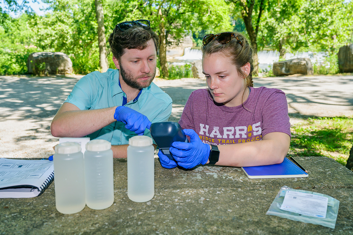 MTSU biology research assistant professor Cole Easson, left, and rising senior Jacqueline Williams of Drummonds, Tenn., check the reading a special pump that will provide data from their Stones River Watershed project that officially begins July and ends next spring when Williams writes her Honors College thesis and presents and one or more conferences. They will map aquatic diversity using next-generation sequencing techniques relative to land use in the surface waters in the river. (MTSU photo by Andy Heidt)