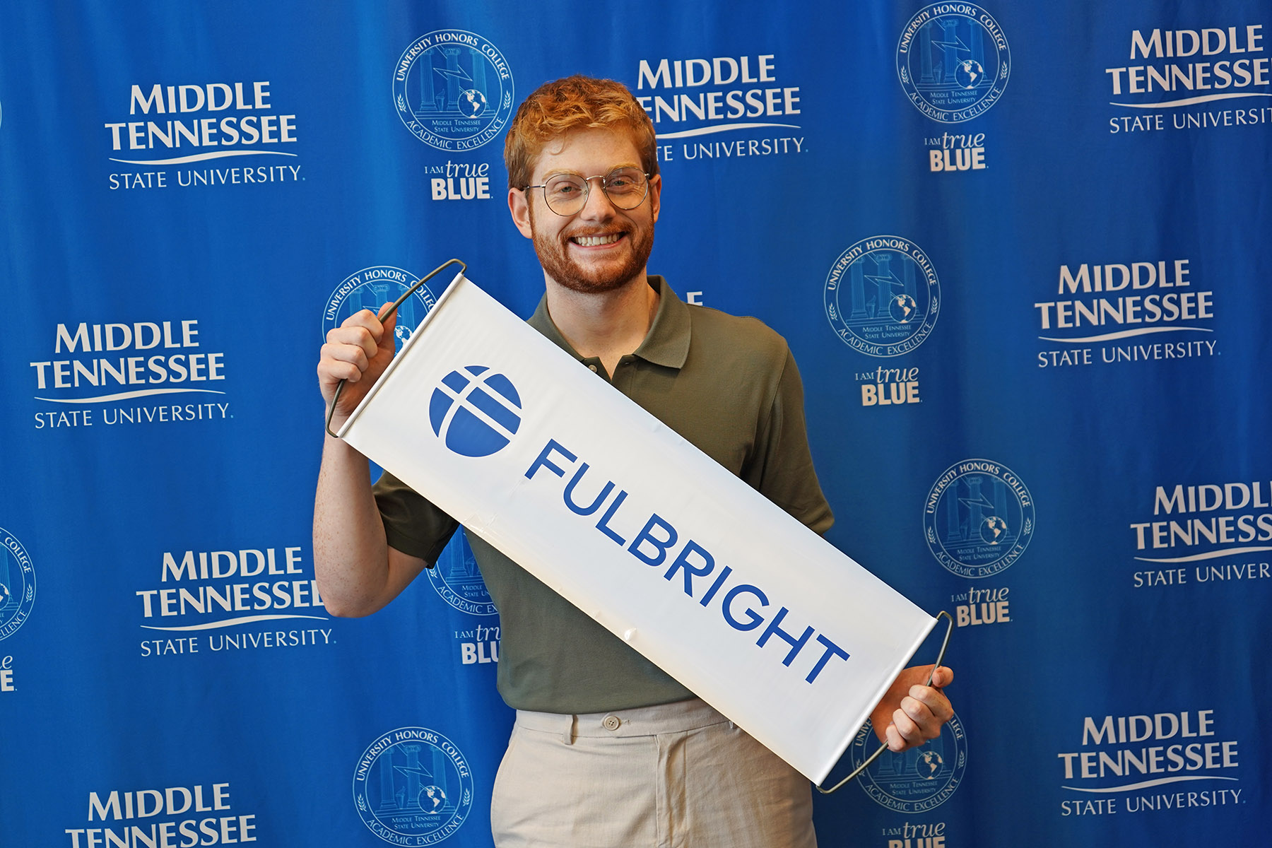 In this spring 2025 photo, Josh Narrell, a May graduate with a master’s in media and communications from Middle Tennessee State University in Murfreesboro, Tenn., holds a sign promoting the Fulbright U.S. Student Program. Recently accepted into the prestigious program, Narrell is preparing to spend nearly a year in Hamburg, Germany, as an English teaching assistant. (MTSU photo by Connie Bartemus)