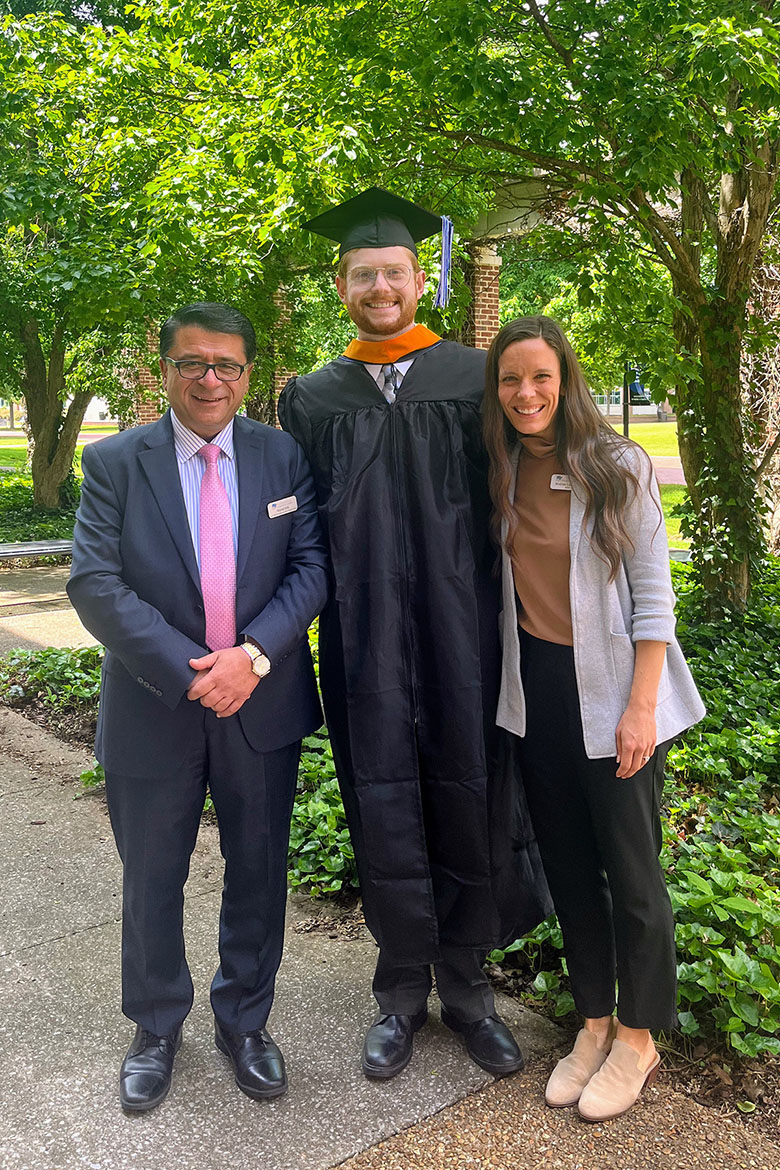 In this spring 2025 photo, Josh Narrell, center, a May graduate with a master’s in media and communications from Middle Tennessee State University in Murfreesboro, Tenn., is pictured in his academic regalia with Murat Arik, left, director of the MTSU Business and Economic Research Center where Narrell worked as a graduate assistant, and BERC executive assistant Andrea Lawrence outside the Paul W. Martin Sr. Honors Building on campus. Recently accepted into the prestigious Fulbright program, Narrell is preparing to spend nearly a year in Hamburg, Germany, as an English teaching assistant. (Submitted photo)
