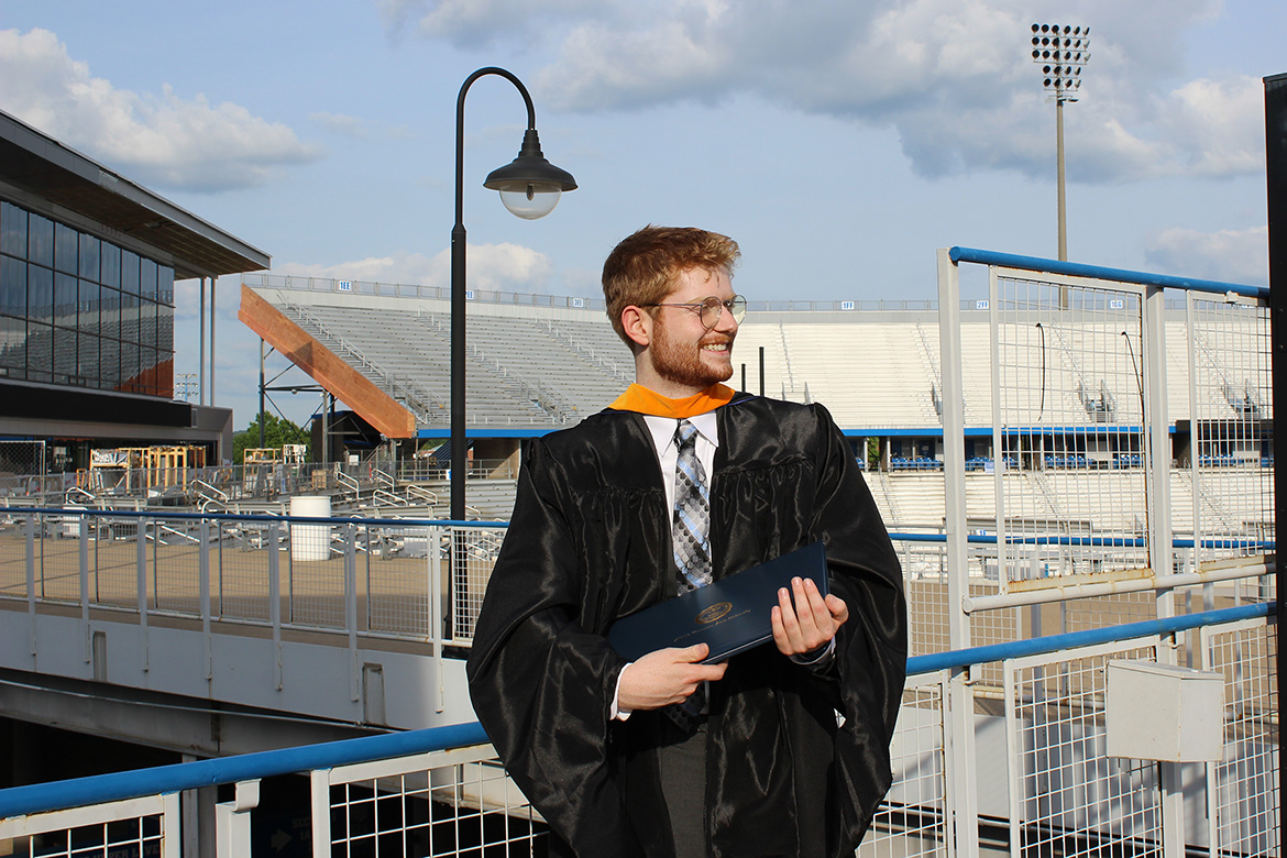 In this spring 2025 photo, Josh Narrell, a May graduate with a master’s in media and communications from Middle Tennessee State University in Murfreesboro, Tenn., is pictured in his academic regalia and holding his diploma cover just outside Floyd Stadium on campus. Recently accepted into the prestigious Fulbright program, Narrell is preparing to spend nearly a year in Hamburg, Germany, as an English teaching assistant. (Submitted photo)