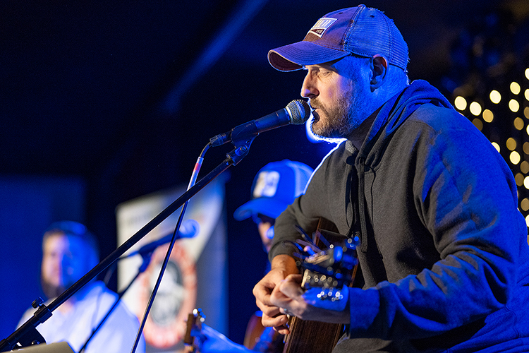 Songwriter and MTSU recording industry alumnus Jason Duke, foreground, concentrates on singing “See the World,” a song about turning frustrating experiences into learning opportunities, as student veteran Ed Watkins, a junior audio production major and newcomer from Charlotte, North Carolina, whose perspective shaped the song, listens in the background during the annual Operation Song writers' retreat at the university. Senior commercial songwriting major Trent Roeder of Rogers, Arkansas, is shown in the center playing guitar. The trio was one of seven who created and performed new songs in MTSU's Keathley University Center Theater at the Oct. 28 event. MTSU's Charlie and Hazel Daniels Veterans and Military Family Center and the Commercial Songwriting Program have hosted Operation Song since 2016. (MTSU photo by Cat Curtis Murphy)