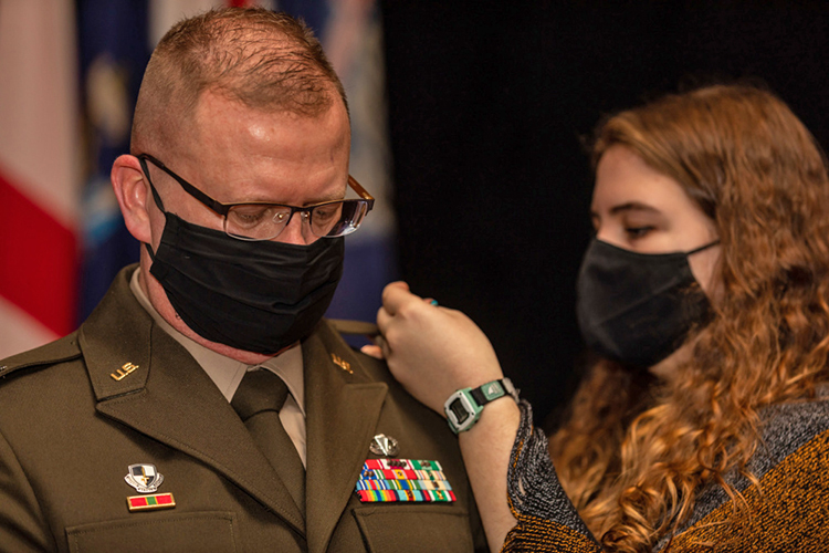 U.S. Army Reserve Brig. Gen. Robert Powell Jr. stands as his wife and daughter pin on the one star single star rank to the shoulders of his Army Green Service Uniform jacket during his promotion ceremony at Fort Gordon, Georgia, Dec. 15, 2020. With the promotion, Powell will serve as the deputy commanding general 335th Signal Command (Theater). (U.S. Army photo by Capt. David Gasperson)