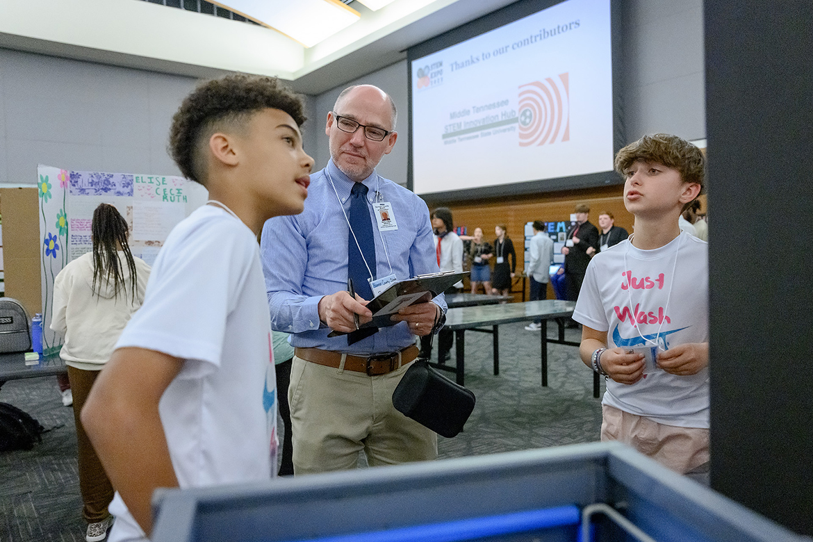 During the recent Middle Tennessee STEM Innovation Hub Expo in the Middle Tennessee State University Student Union Ballroom, Sumner County Schools’ STEM coordinator Ben Bruce, center, listens as Jayden Lee, 11, left, of Hendersonville, Tenn., talks about the STEM research project, “Just Wash It,” he and Skylar Ginn, 11, of Hendersonville, collaborated on this year. Lee and Ginn attend Madison Creek Elementary School in Goodlettsville, Tenn. (MTSU photo by J. Intintoli)