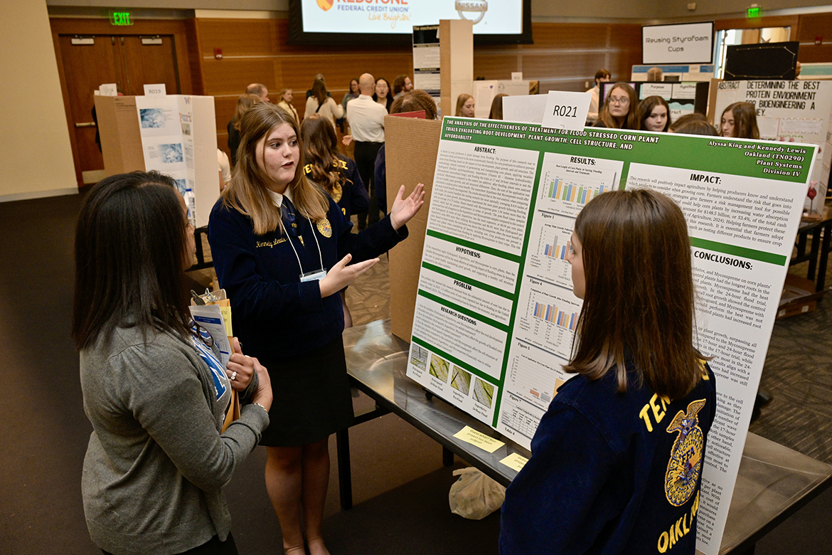 Event judge Andrea Reed, an MTSU graduate student in Mathematics and Science Education who works in the Middle Tennessee State University Tennessee STEM Education Center, listens while Oakland High freshman Kennedy Lewis, center, of Lascassas, Tenn., explains the agricultural research she and freshman Alyssa King, of Murfreesboro, Tenn., conducted during the school year. It was part of the annual Middle Tennessee STEM Innovation Hub STEM Expo, held Wednesday, April 3, in the Student Union Ballroom on the MTSU campus in Murfreesboro, Tenn. (MTSU photo by Andy Heidt)