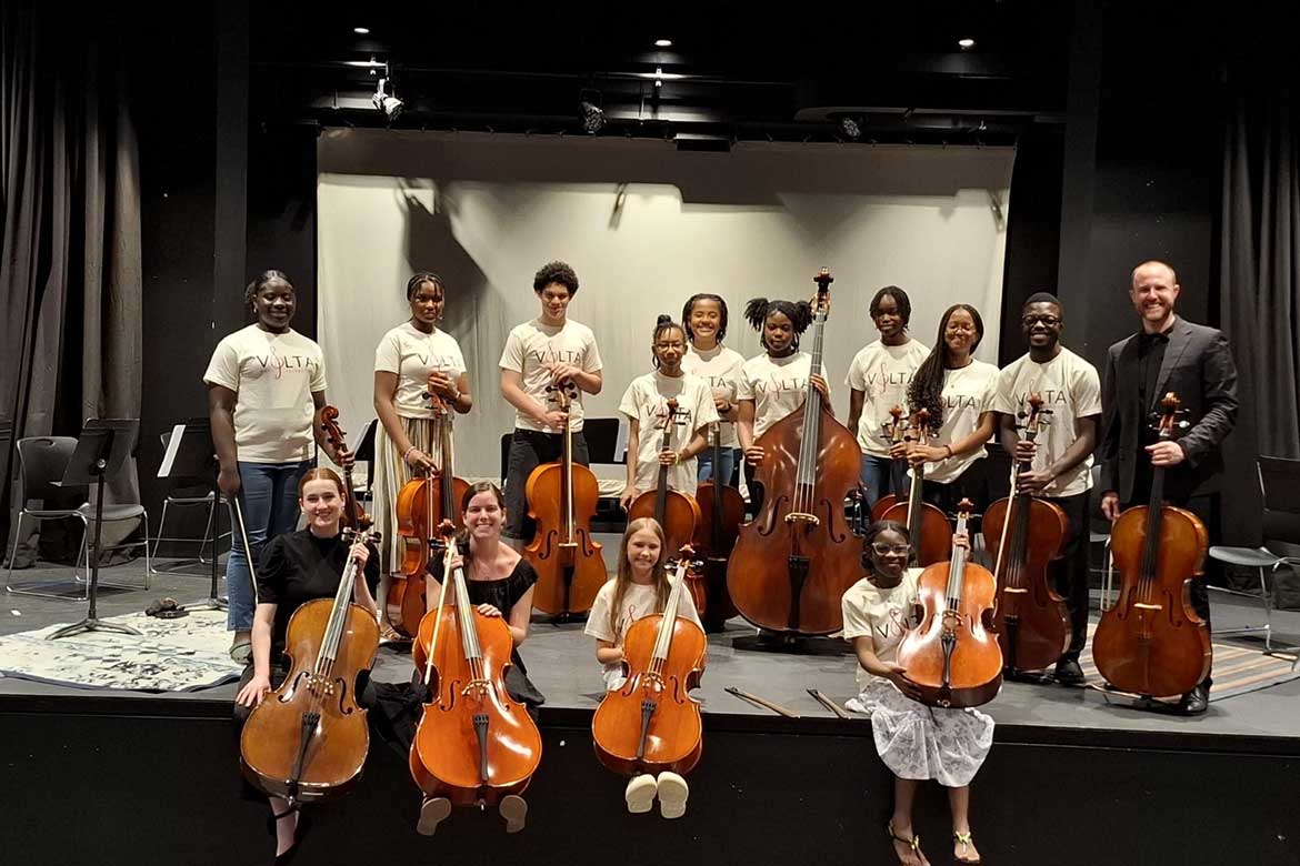 In this February 2025 photo, Middle Tennessee State University School of Music assistant music professor Bryan Hayslett, far right, graduate assistant Jayna Powell, bottom left, and senior Annalisa Thomas pose for a photo with 11 students who performed in a concert after attending a three-day cello workshop the trio led at John Gray High School in George Town, Cayman Islands thanks to the Florida-based Volta Music Foundation. (Photo submitted)