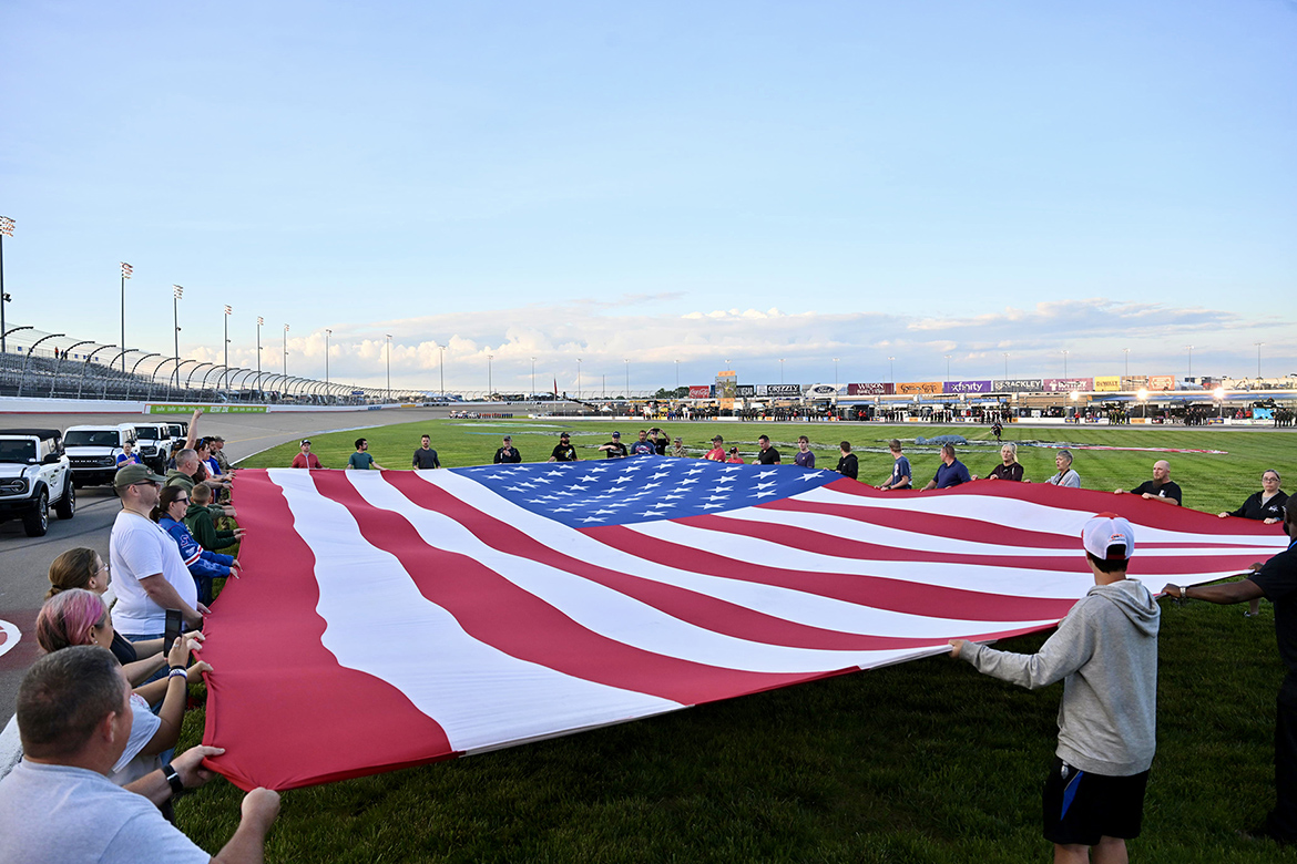 About 75 military-connected family members organized by the Charlie and Hazel Daniels Veterans and Military Family Center at Middle Tennessee State University unfurl a giant American flag in the infield at Nashville Superspeedway in Lebanon, Tenn., before the May 30 Rackley Roofing 200. (MTSU photo by James Cessna)