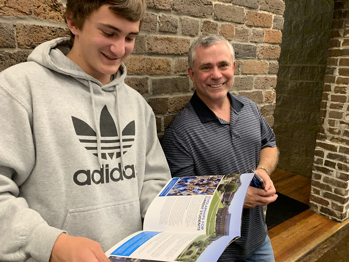 A member of the Middle Tennessee State University True Blue 100 as a freshman in the 2019-20 academic year at Hall High School, Nathan Morgan, left, reviews Admissions Office recruiting material as his father, Robert Morgan, observes during the annual MTSU True Blue Tour event Oct. 24 at The Foundry On the Fair Site in Knoxville, Tenn. Each year, MTSU staff identify the top 100 freshmen scholars in Tennessee. (MTSU photo by Randy Weiler)