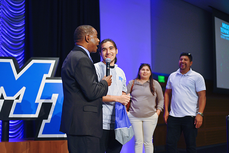 Middle Tennessee State University President Sidney A. McPhee awards prospective student Jonathan Eskobar a $15,000 scholarship while his parents, Maria and Saulramos Eskobar, look on during the kickoff event for the university’s True Blue Tour at the Student Union Building on Wednesday, Aug. 17, 2022. (MTSU photo by Cat Curtis Murphy)