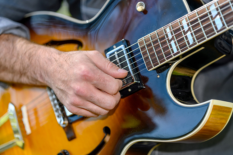 This closeup shot shows professional guitarist and student Beau Tackett, a student in the Master of Music program, picking his guitar in Walnut Grove. (MTSU photo by J. Intintoli)