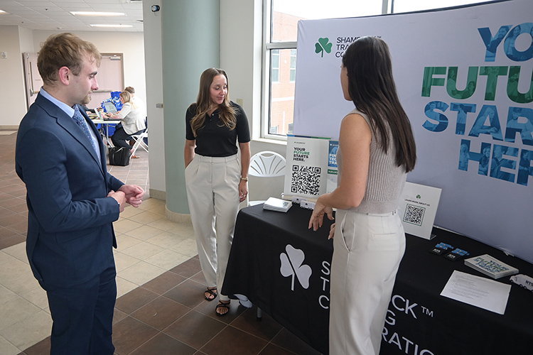 Representatives with Shamrock Trading Corp. share information with a Middle Tennessee State University student at the 2025 Tech Vision Conference held April 10-11 in the Miller Education Center atrium on Bell Street on the MTSU campus in Murfreesboro, Tenn. Shamrock was among industry vendors who sent representatives to the event to network with students. (MTSU photo by Jimmy Hart)