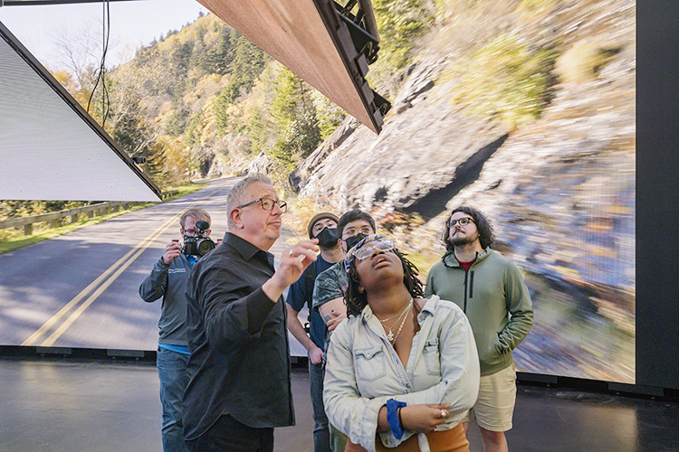 David Bennett, vice president of business development at Monolith Studios, talks with MTSU media students while footage from a mountain drive plays on an LED screen behind them during production for a "teaser" commercial in Nashville for the Department of Media Arts' new extended reality, or XR, stage, a new type of film and video production stage that will enable them to create projects anywhere, anytime. Monolith Studios has advised MTSU on its new setup for its XR facility, the only one of its kind at a Tennessee university, which will be ready for classes this fall. (MTSU photo by Andy Heidt)