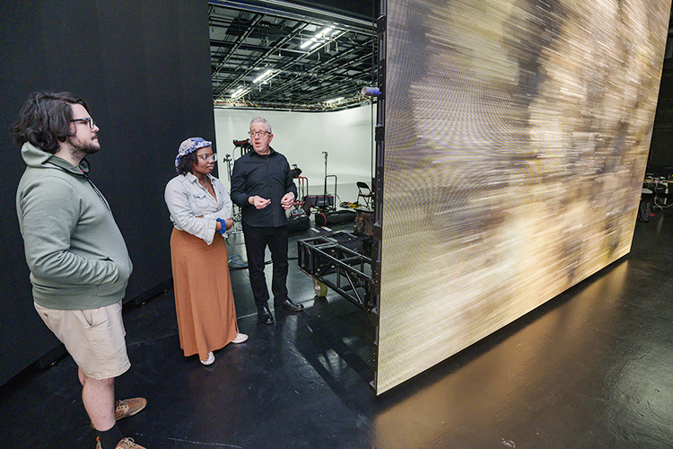 David Bennett, vice president of business development at Monolith Studios, talks with MTSU media students as footage of a speedy drive down a mountain road plays on an LED screen beside them during production for a "teaser" commercial in Nashville for the Department of Media Arts' new extended reality, or XR, stage, a new type of film and video production stage that will enable them to create projects anywhere, anytime. Monolith Studios has advised MTSU on its new setup for its XR facility, the only one of its kind at a Tennessee university, which will be ready for classes this fall. (MTSU photo by Andy Heidt)