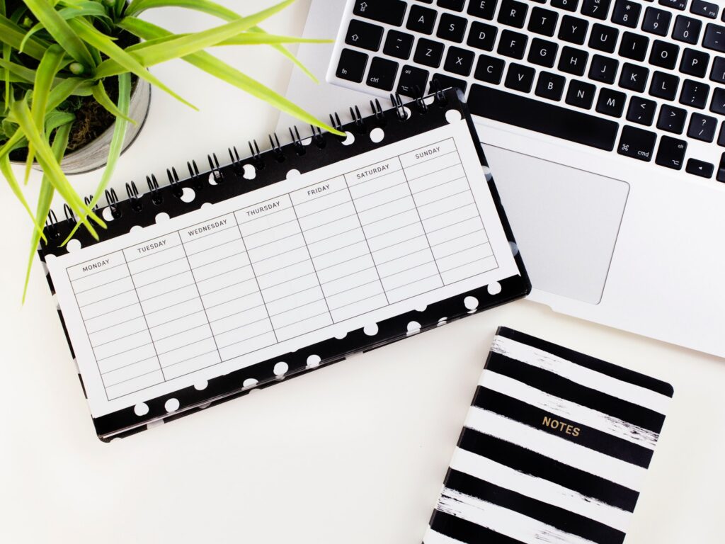 Laptop, plant, and planner, and notebook on a white desk. Photo by Emma Matthews Digital Content Production on Unsplash