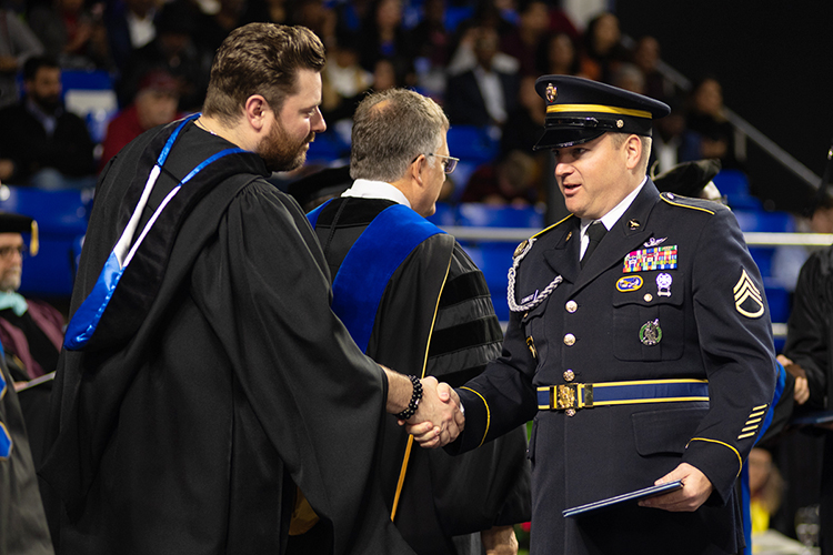 New MTSU aerospace graduate James D. Summers of Woodbury, Tennessee, center, accepts congratulations from country music entertainer, former MTSU student and guest speaker Chris Young during the Class of 2019's morning commencement ceremony inside Murphy Center on Saturday, Dec. 14. (MTSU photo by James Cessna)