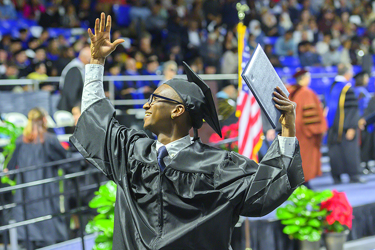 A new MTSU graduate, degree in hand, waves to family and friends inside Murphy Center Saturday, Dec. 14 at the university's fall 2019 afternoon commencement ceremony. (MTSU photo by Cat Curtis Murphy)