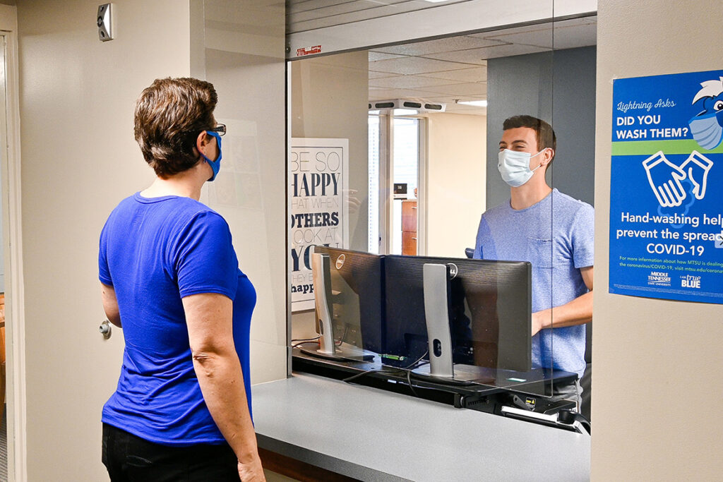 Michael Walters, a graduate assistant, helps Melissa Houghton, graduate analyst, with a question in the front lobby of the MTSU College of Graduate Studies on Oct. 15, 2020. (MTSU photo by Stephanie Barrette)