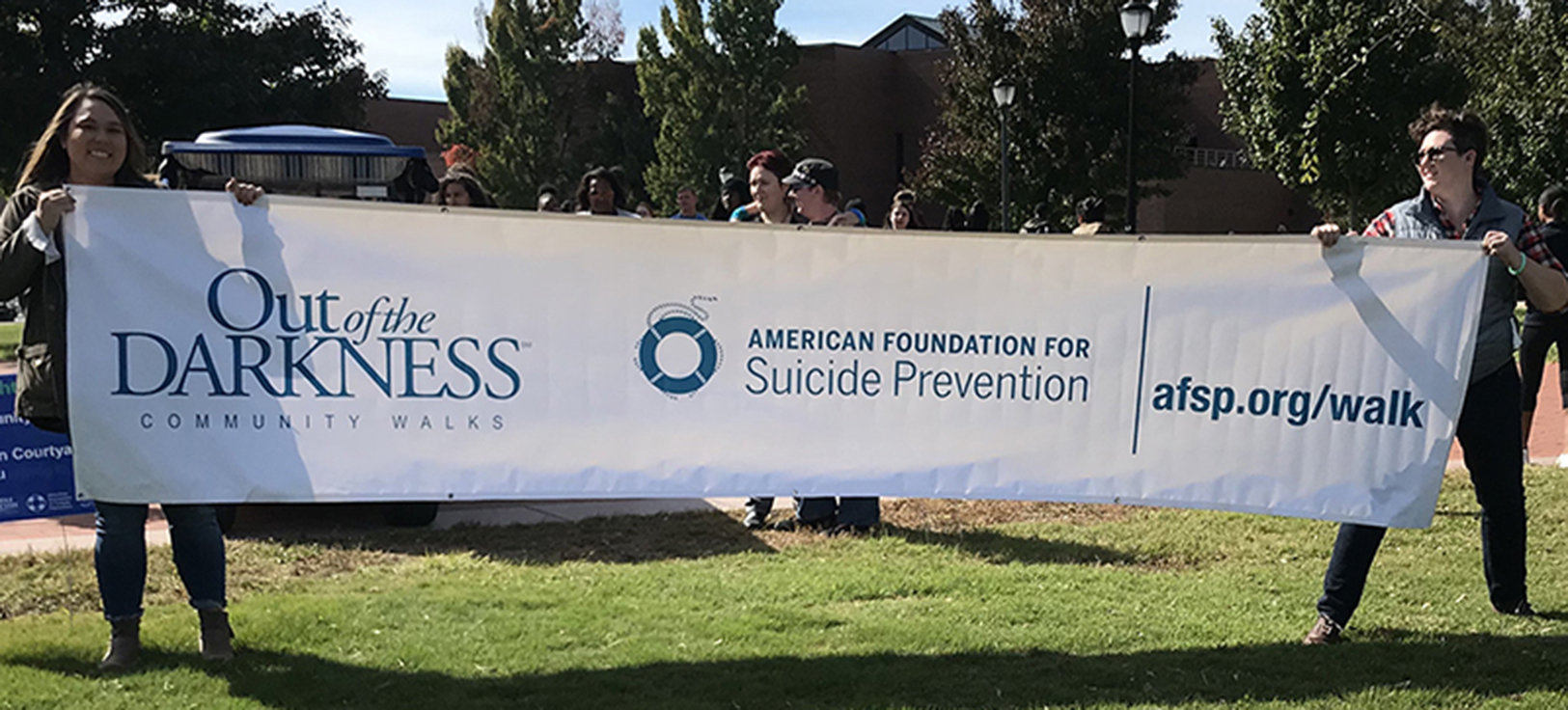MTSU graduate students Lisa Hattaway, left, and Sarah Elmer, both social work majors, hold a banner touting community walks promoting suicide awareness at the 2018 Hike for Life. (Photo submitted)