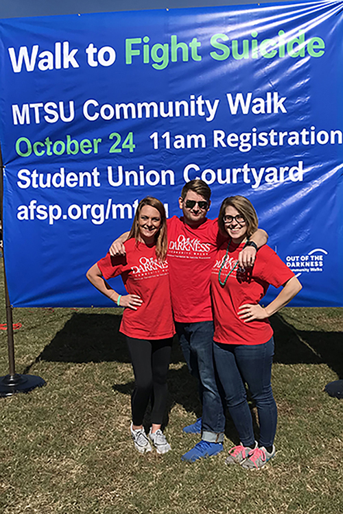 Organizers of Hike for Hope pose in front of a banner during the 2018 event. From left, Kat Cloud, Tennessee area director for the American Foundation for Suicide Prevention; Justin Bucchio, assistant professor of social work and coordinator of the social work master’s degree program; and Sarah Pope, psychology major. (Photo submitted)