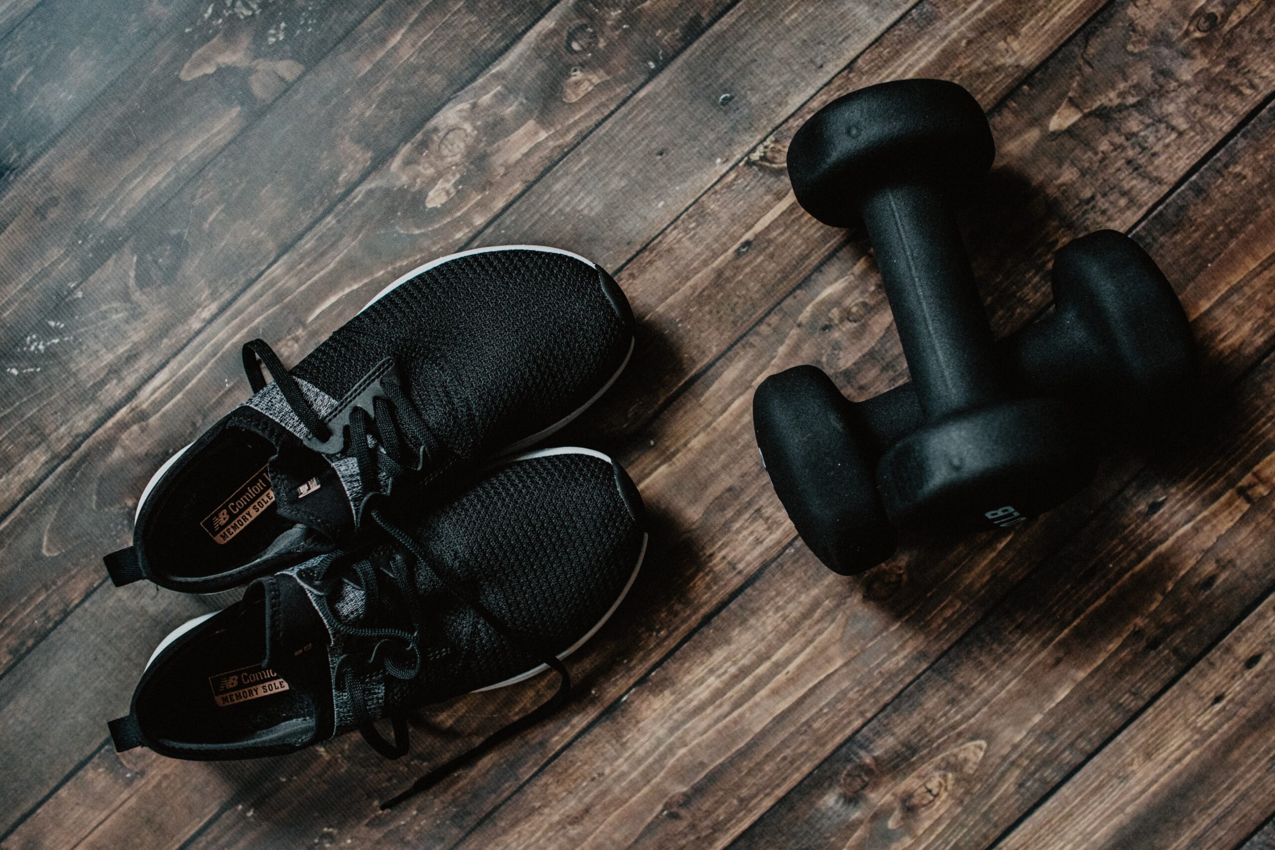 Tennis shoes and weights on a hardwood floor. Photo by Kelly Sikkema on Unsplash