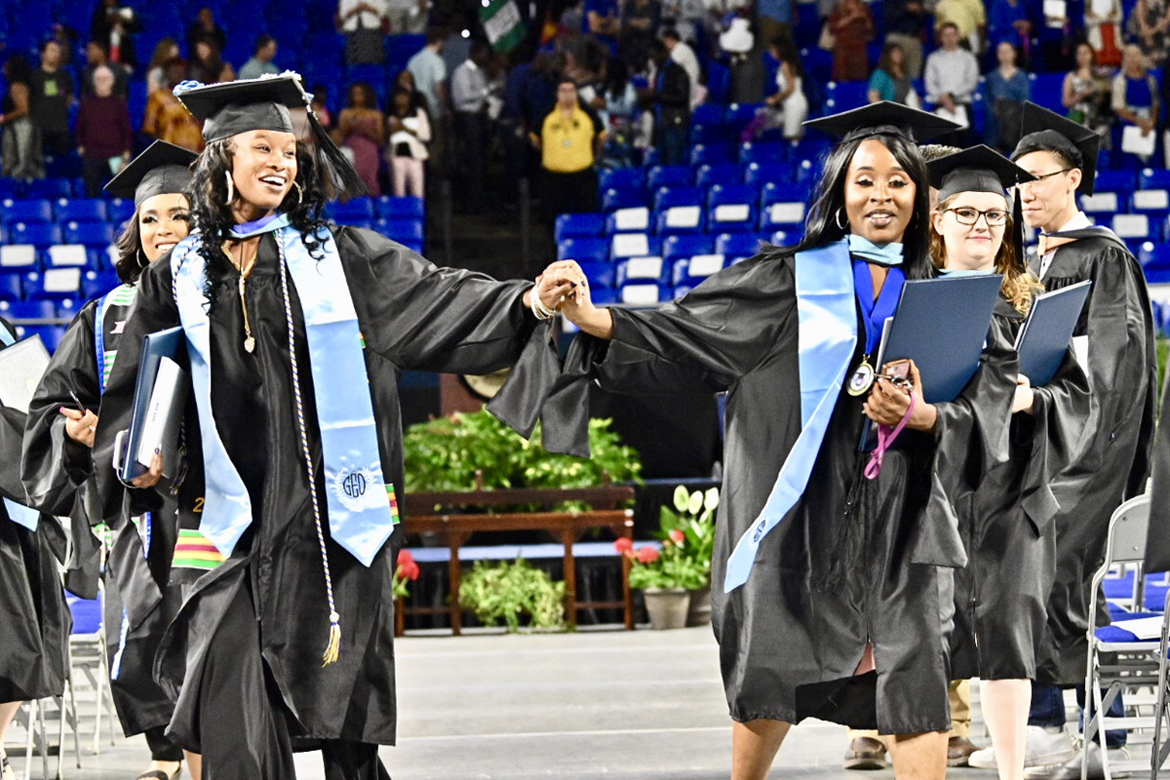 A pair of joyful spring 2019 MTSU graduates clutch their new advanced degrees in education and hold hands as they file out of Murphy Center during the university’s College of Graduate Studies May 2019 commencement ceremony. MTSU will present more than 800 students with degrees in the summer 2019 commencement ceremony set Saturday, Aug. 10. (MTSU file photo by J. Intintoli)