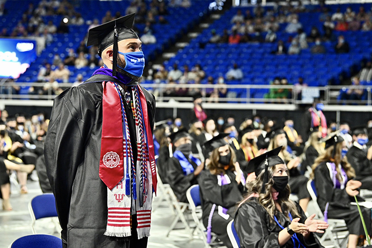 A graduating student-veteran, wearing a special red stole designating his military service, stands inside MTSU's Murphy Center as he and other service members are recognized Friday, May 7, during the first day of the university's spring 2021 commencement ceremonies. Students returned to Murphy Center May 7-9 for the first time since 2019 for a three-day, 10-event, socially distanced commencement weekend. (MTSU photo by J. Intintoli)