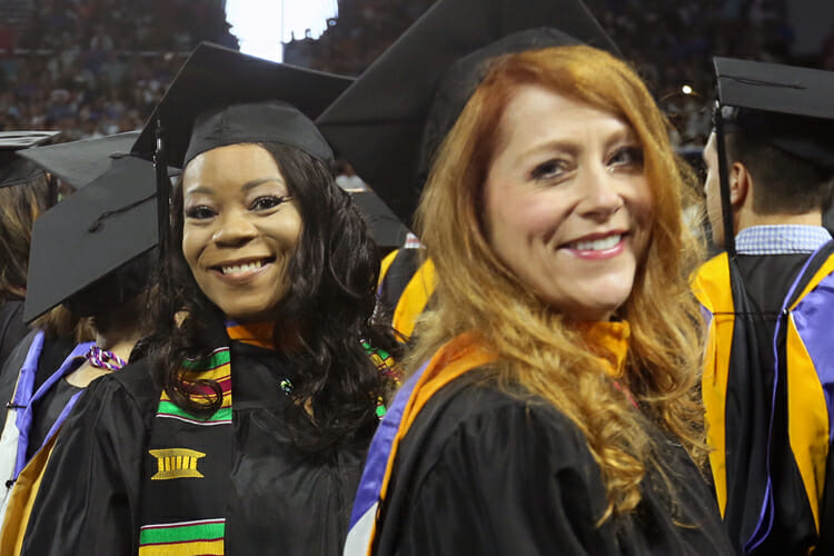 Two summer 2018 MTSU graduates smile as they stand in line during the August commencement ceremony in Murphy Center. MTSU will present 1,731 degrees at its two fall 2018 commencement ceremonies, set at 9 a.m. and 1:30 p.m. Saturday, Dec. 15. (MTSU file photo by GradImages.com)