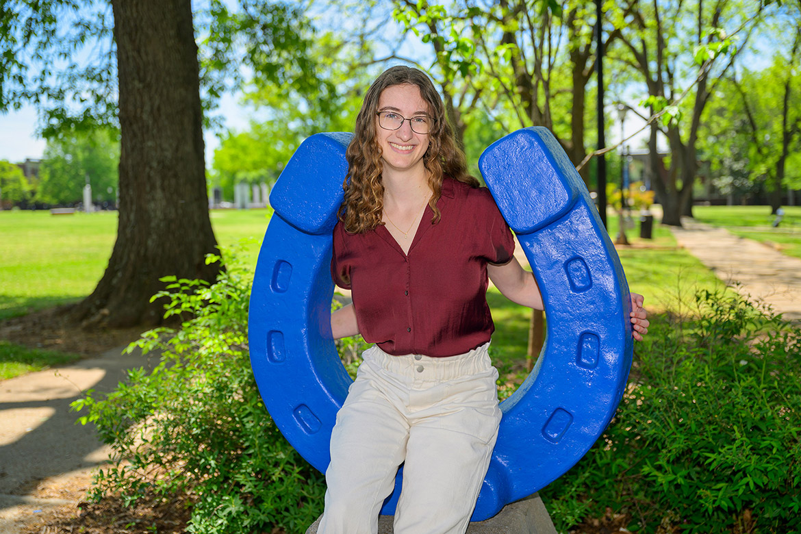 Student sitting on blue horseshow in Walnut Grove at MTSU.